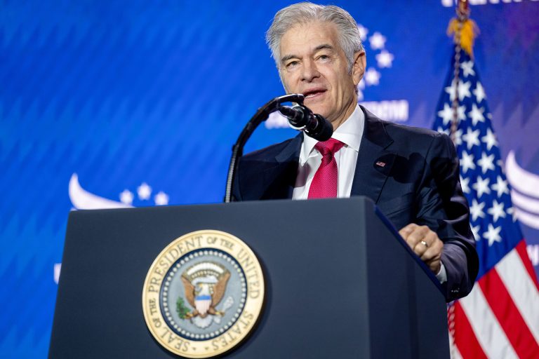 A man with white hair stands behind a lectern with the seal of the President of the United States on it, and speaks into a microphone.
